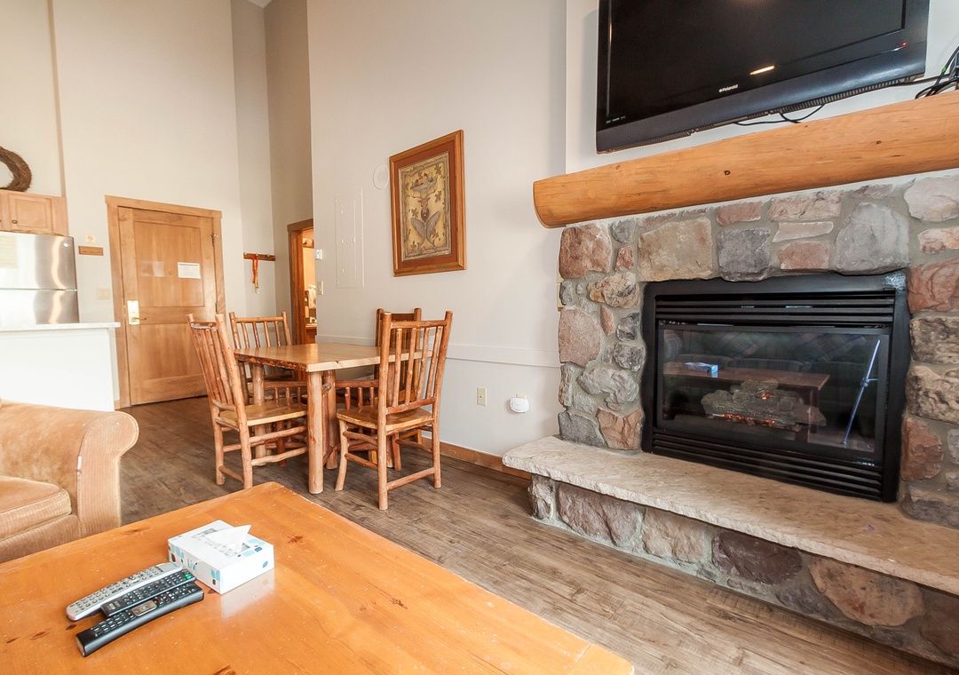 Cozy up in your mountain-style living space with stone fireplace, wood beams, and rustic dining nook perfect for intimate meals.