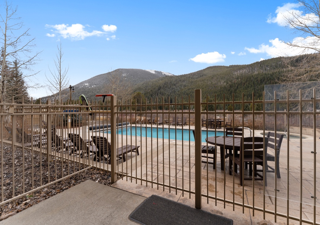 Mountain resort pool deck with forested peaks creating a stunning alpine backdrop for the outdoor swimming area.