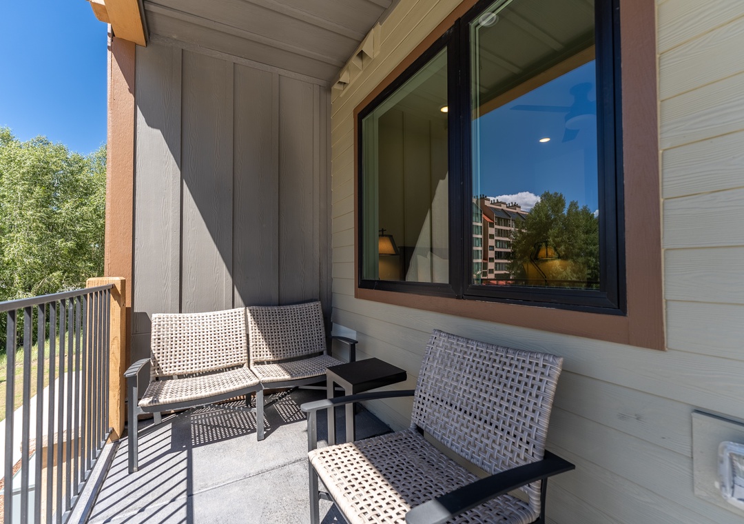 Relax on your private balcony with comfortable seating and enjoy peaceful tree-lined views.