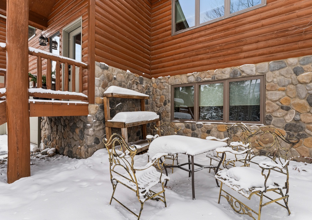Your private patio offers rustic charm with stone accents and log construction, creating a cozy outdoor retreat even in winter's embrace.
