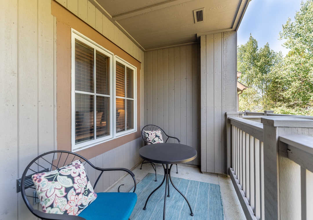 Unwind on your private covered balcony with comfortable seating and peaceful tree views.