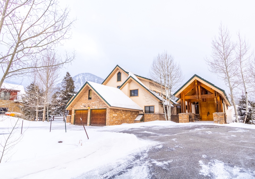 Beautiful mountain lodge with snow-dusted rooflines and warm timber accents nestled in a winter wonderland setting.