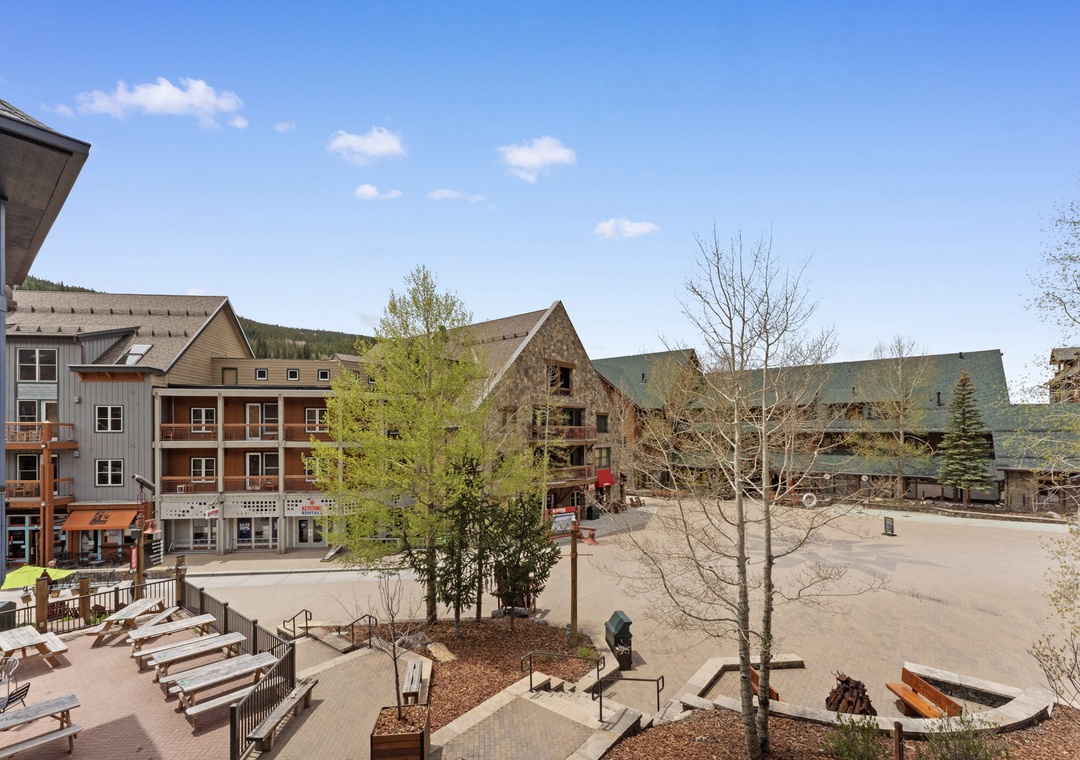Charming mountain village setting with rustic buildings and peaceful courtyard plaza surrounded by forested hills.