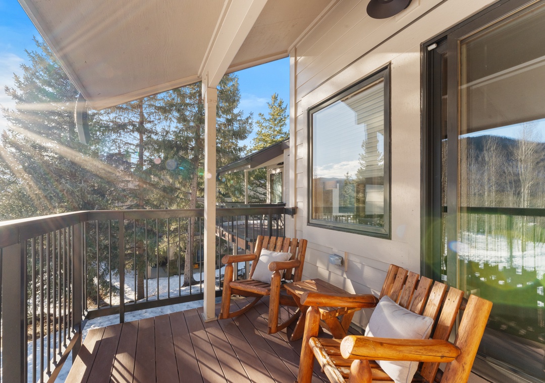 Step onto your private balcony where wooden chairs invite you to sip morning coffee while sunlight filters through towering evergreens.