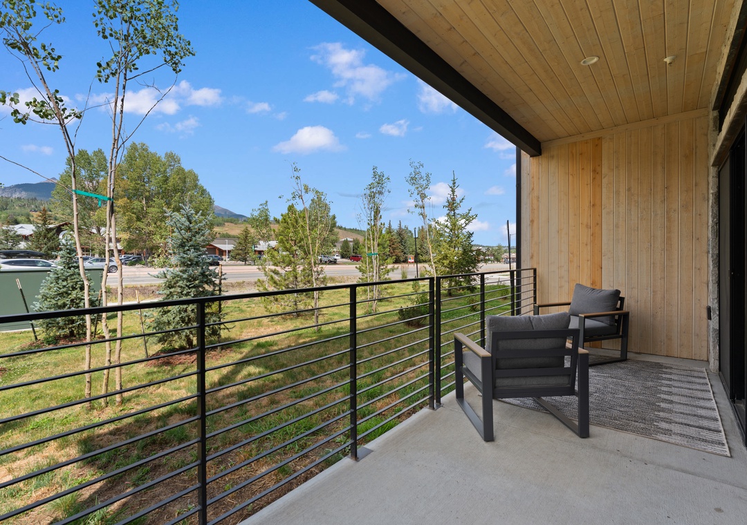 A private covered balcony with comfortable seating overlooks scenic mountain landscapes and nearby neighborhoods, offering the perfect spot to savor your morning coffee or unwind in the evening breeze.