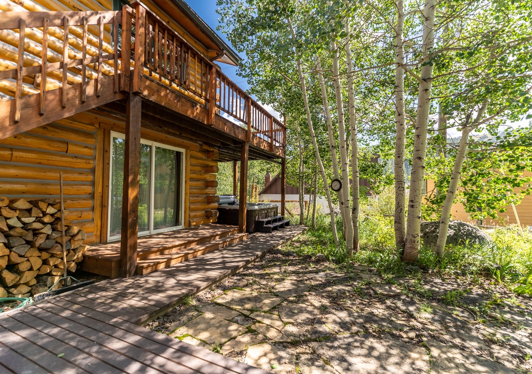 Charming log cabin nestled among towering aspen trees with rustic wood decking and mountain ambiance.