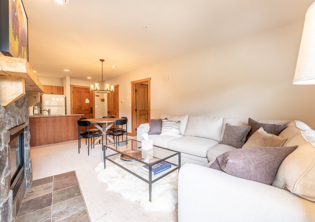 Relax in your spacious living room with plush sectional seating, modern fireplace, and open kitchen perfect for entertaining.