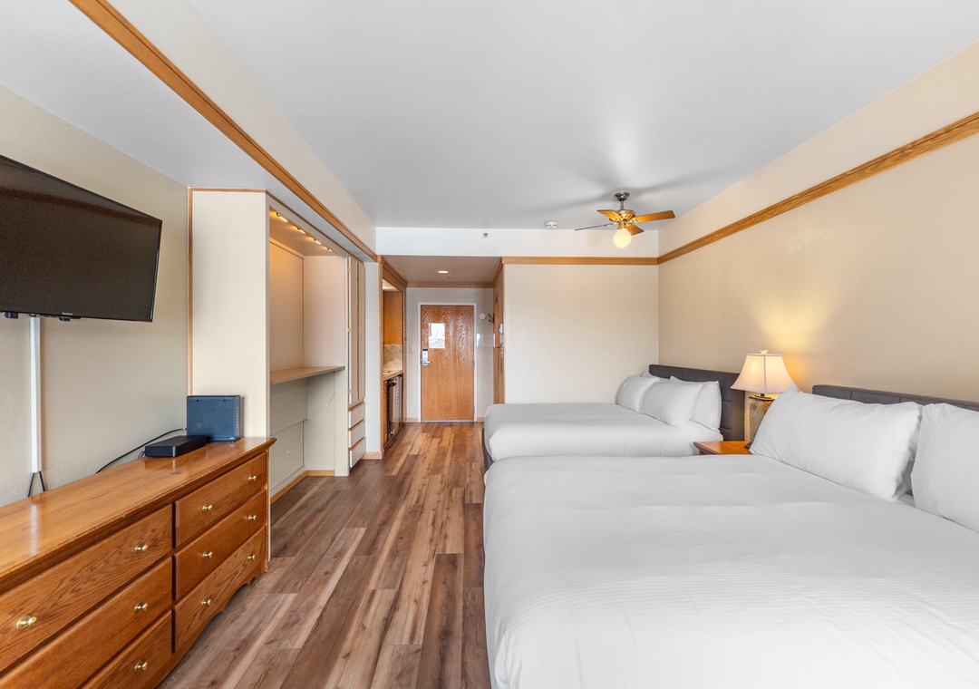 Relax in your spacious room featuring two comfortable beds, modern furnishings, and convenient amenities for a perfect stay.