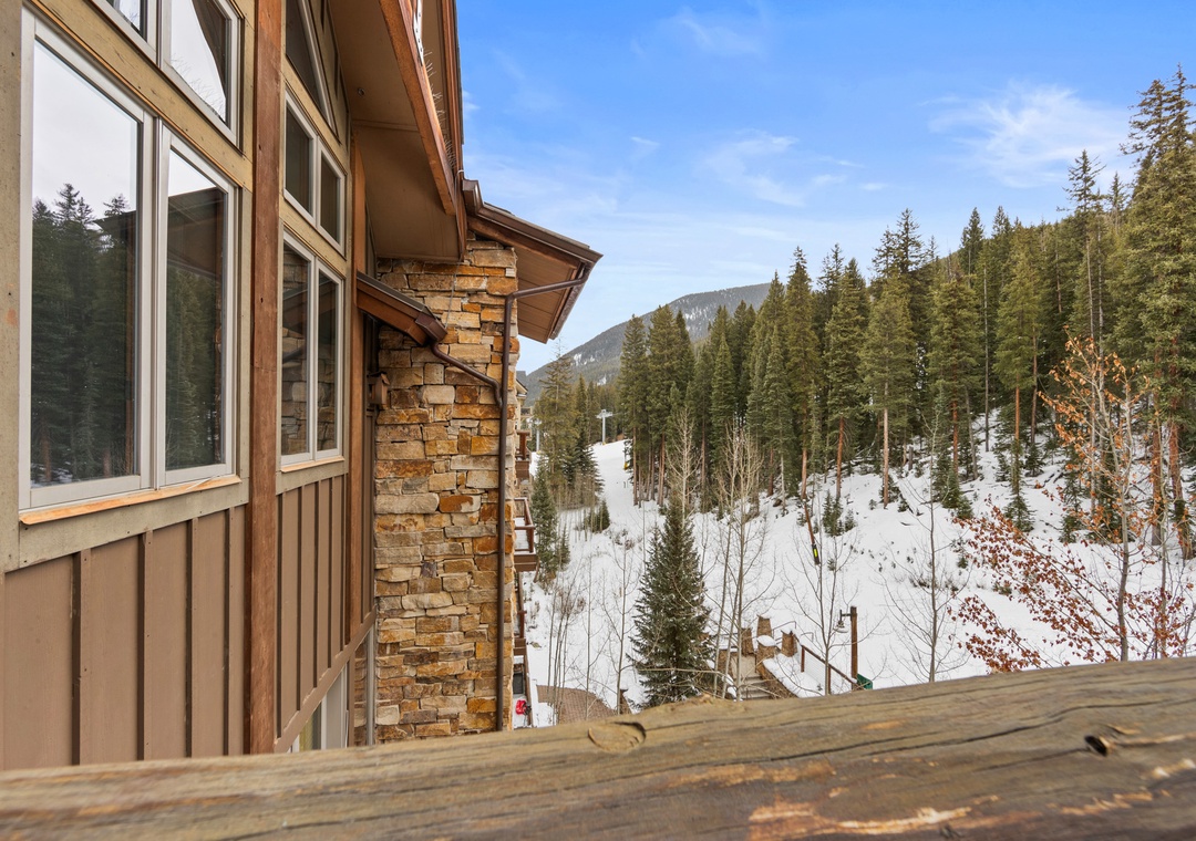 Mountain lodge nestled in snow-covered forest with direct ski slope access nearby.