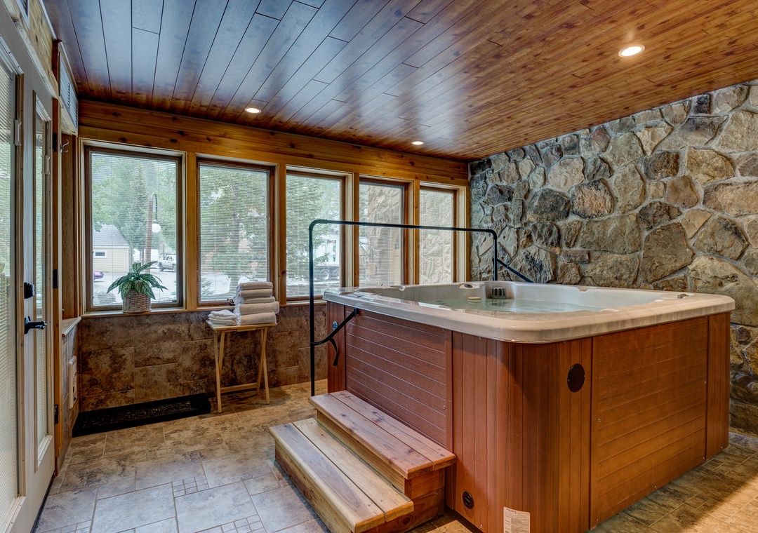 Unwind in your private hot tub surrounded by rustic stone walls and panoramic windows—the perfect retreat.