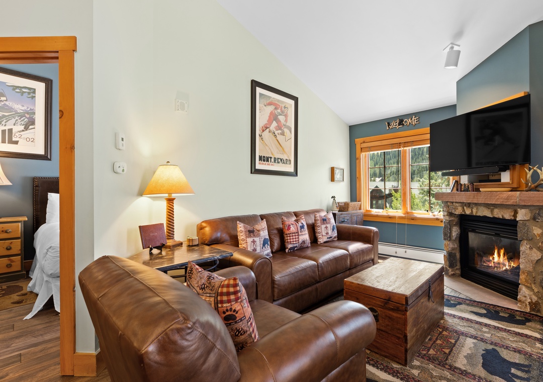 Sink into rich leather sofas and cozy up by your stone fireplace. Natural light streams through the windows, framing mountain views as you relax in this inviting alpine retreat.