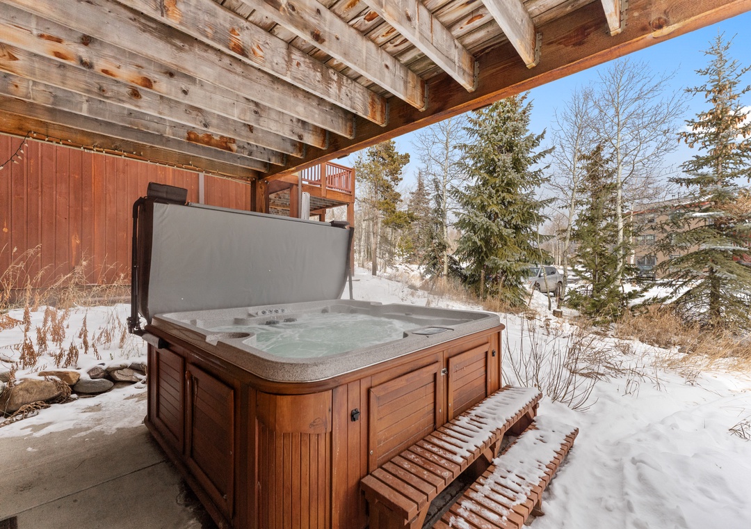 Soak in your private hot tub while snow glistens on evergreens around you, creating the perfect winter mountain retreat.