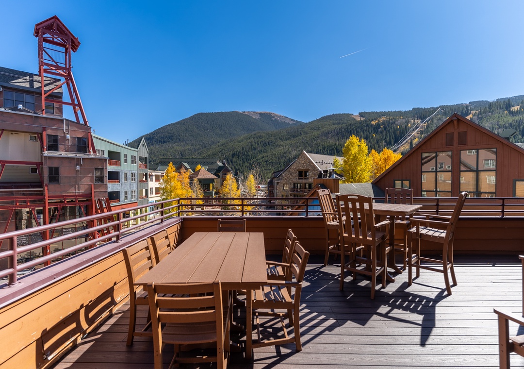 Scenic mountain views from a spacious deck dining area with golden autumn foliage and rustic alpine buildings.