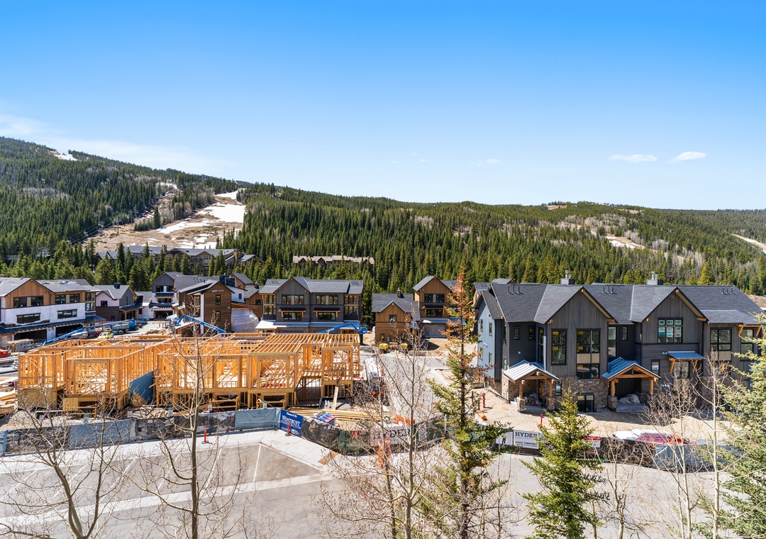 Mountain resort development nestled in forested valley with ski slopes visible on distant peaks.
