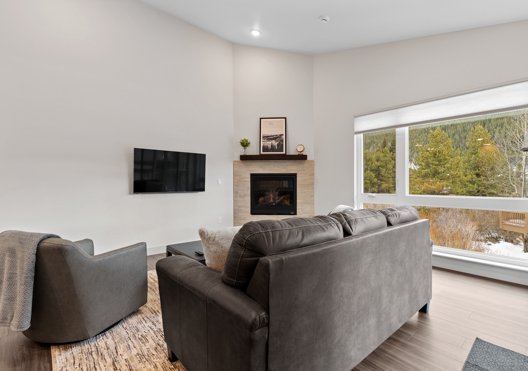 Unwind in your spacious living room where plush sofas face a cozy fireplace, while large windows frame stunning mountain views.