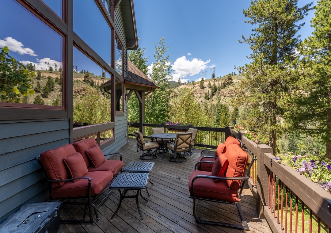 Unwind on your private deck with panoramic mountain views, surrounded by comfortable seating and vibrant flowers in nature's embrace.