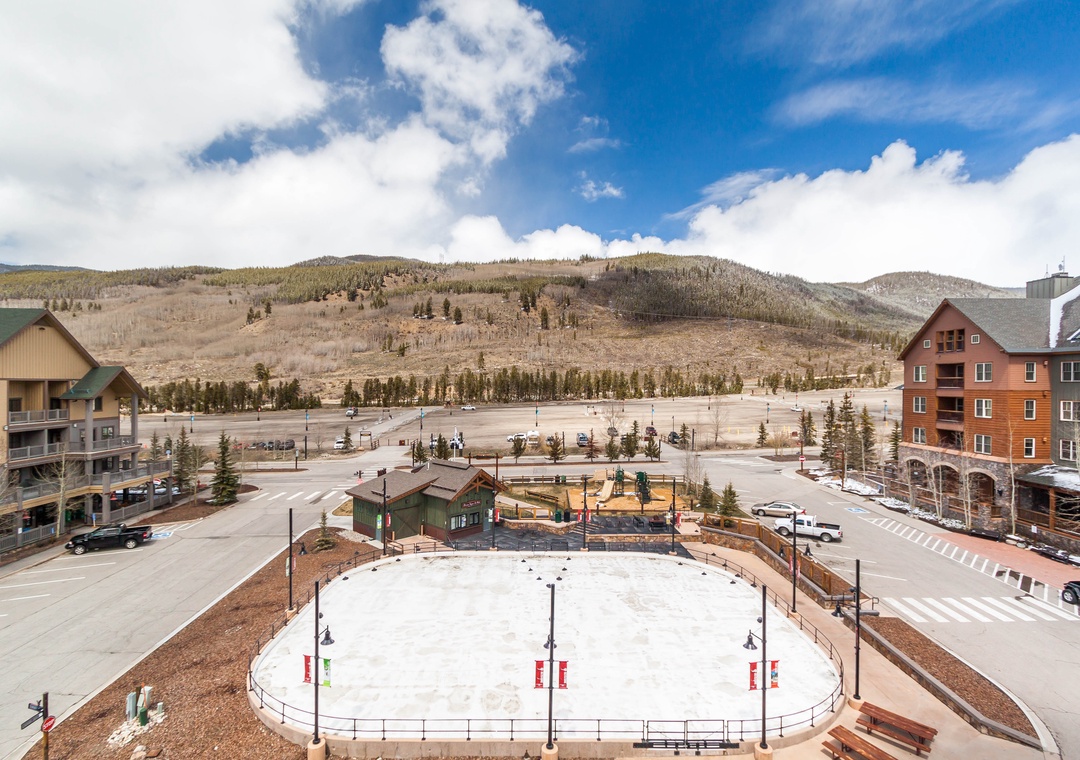 Mountain resort village with ice rink, ski facilities, and forested hills creating a perfect alpine getaway destination.