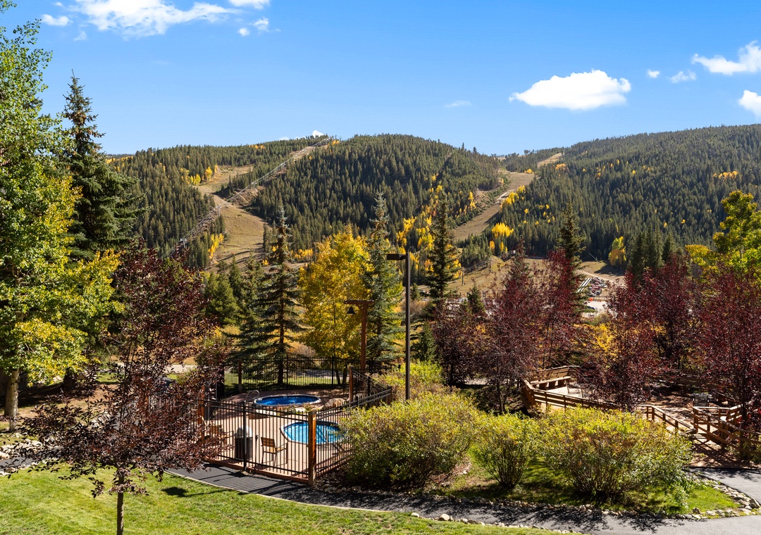 Mountain resort with heated pool surrounded by autumn foliage and ski slopes.
