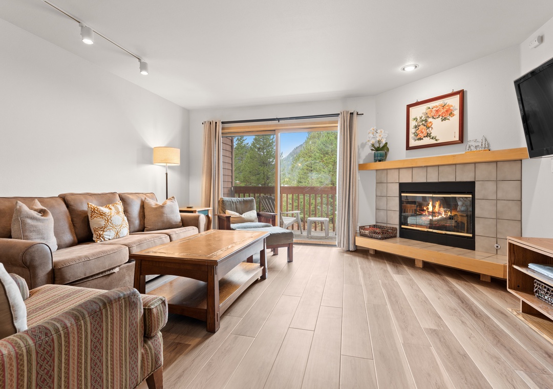 Settle into your cozy living room where warm mountain views await just beyond the balcony. Light the fireplace, sink into plush seating, and let the natural light and alpine scenery make you feel right at home.
