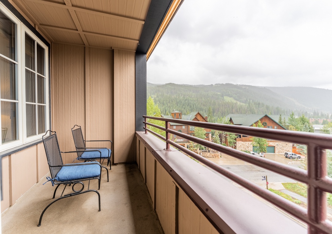 Your private balcony offers stunning mountain views while you relax in comfortable seating, surrounded by peaceful forest scenery.