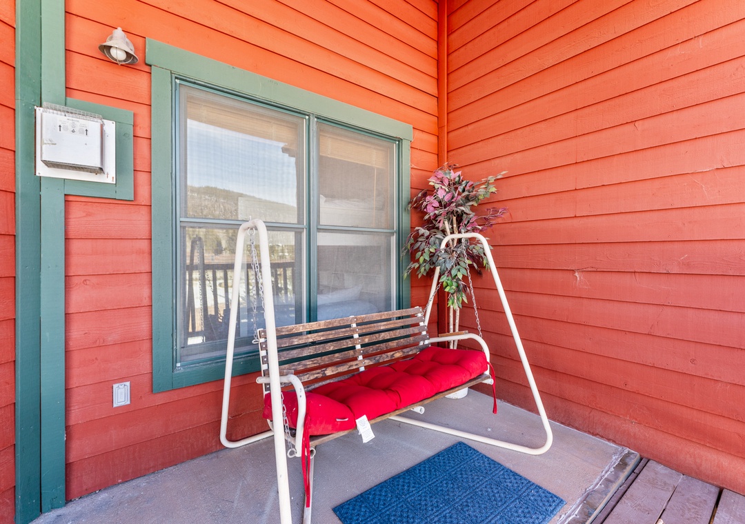 Relax on your private swing with red cushions, surrounded by charming coral siding and peaceful mountain views beyond.