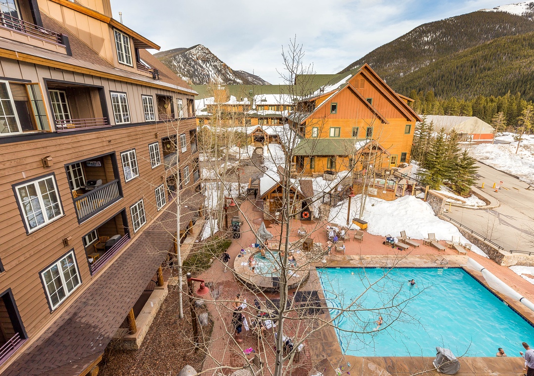 Mountain resort property featuring outdoor pool, wooden architecture, and snow-capped peaks in the surrounding area.