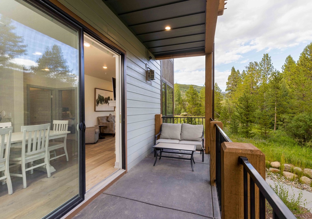 Relax on your private balcony with forest views, where comfortable seating invites peaceful moments overlooking nature's beauty.