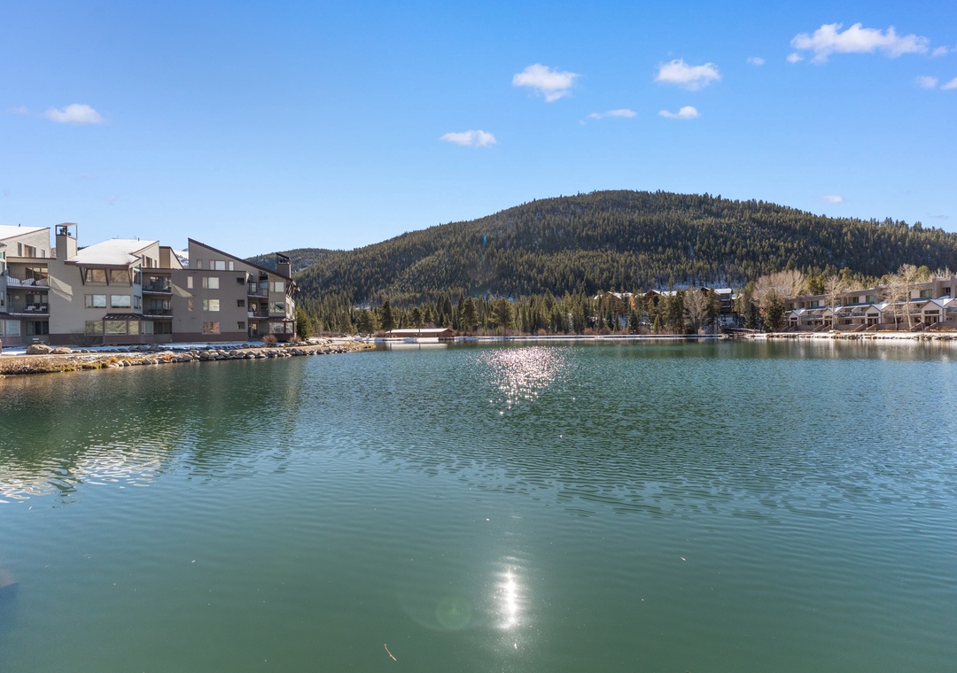 Scenic lakeside location with mountain views and modern residential buildings creating a peaceful waterfront setting.