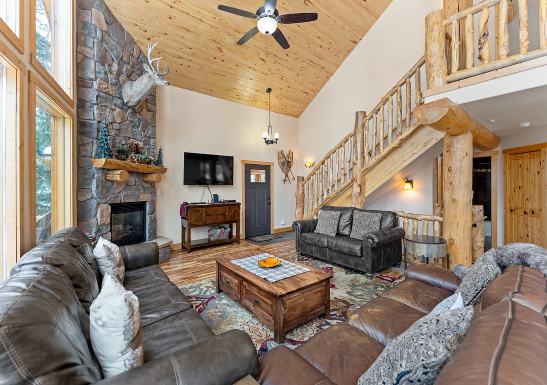 Sink into plush leather seating by your crackling stone fireplace, where rustic log beams and soaring ceilings create the perfect mountain retreat atmosphere.