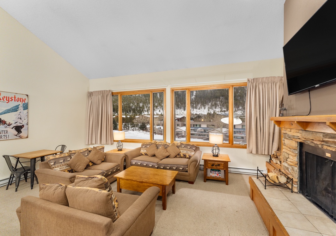 Cozy up by your stone fireplace while enjoying snowy mountain views through expansive windows in this warm, ski-themed retreat.