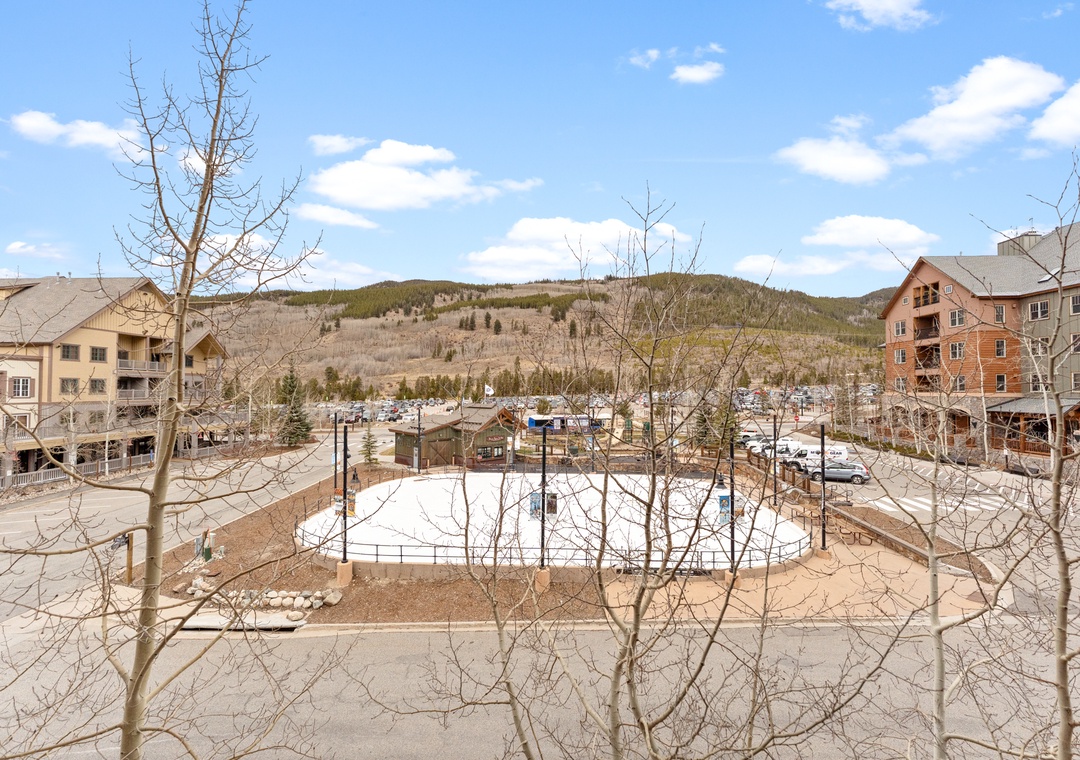 Mountain town setting with recreational facilities and ski resort buildings surrounded by forested hills.