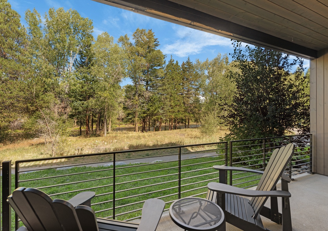 Step onto your private balcony and take in the peaceful natural landscape, where towering pines and golden grasses frame your serene retreat under open skies.