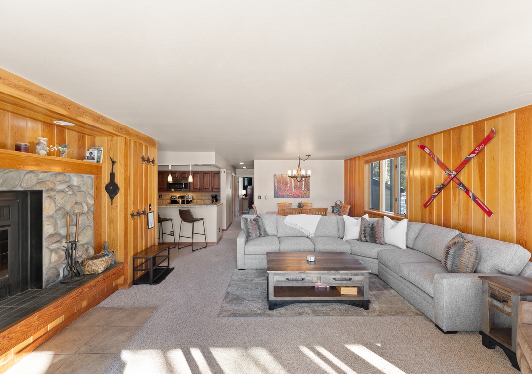 Relax in this spacious living area with plush sectional seating and a cozy stone fireplace, where warm wood accents create the perfect mountain retreat atmosphere.
