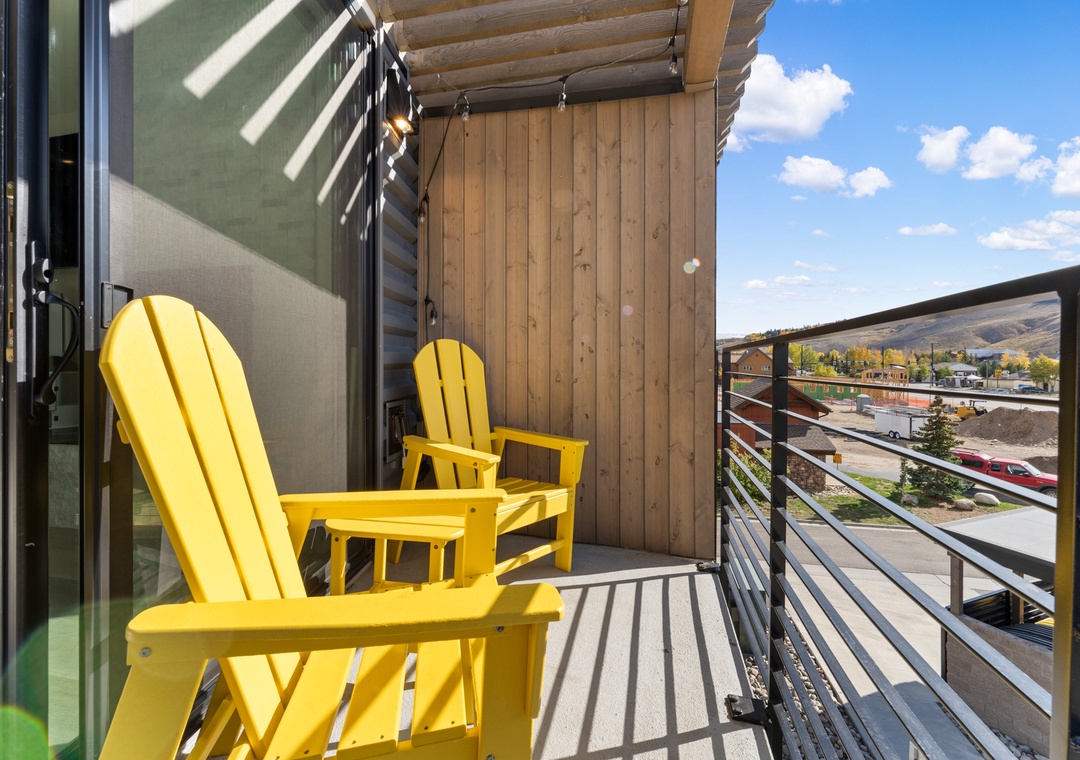 Relax in your cheerful yellow chairs on this sunny balcony, where mountain views and blue skies create the perfect backdrop for your morning coffee.