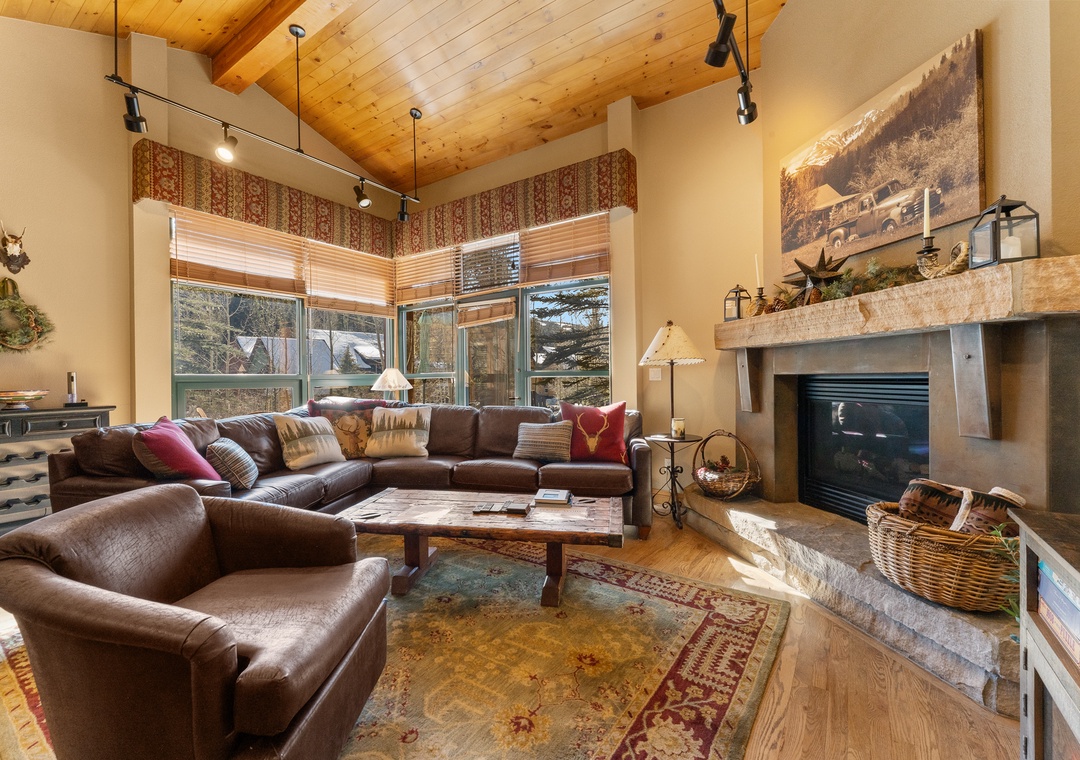 Sink into plush leather sofas by your crackling fireplace, where rustic charm meets mountain elegance in this inviting living space.
