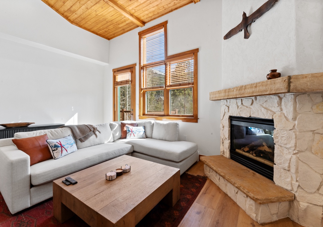 Cozy up by your stone fireplace with exposed wooden beams overhead and forest views through large windows.