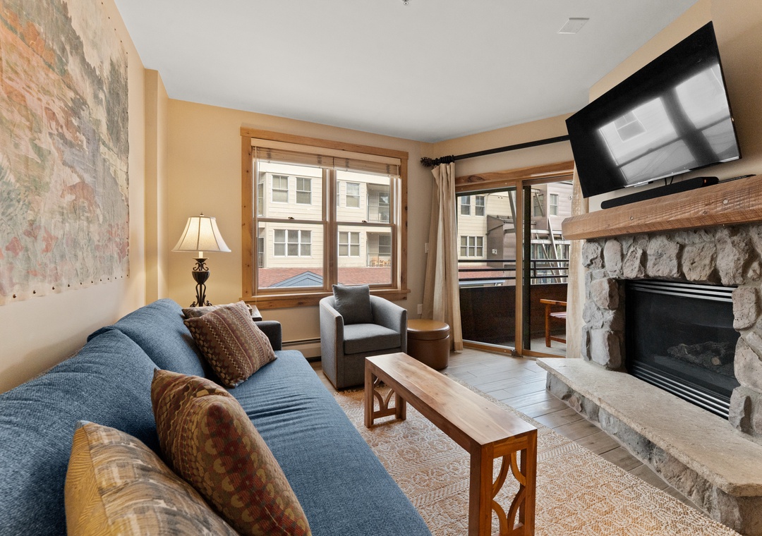 Sink into the cozy sofa beside a warm stone fireplace, with mountain air just steps away on your private balcony and modern entertainment at your fingertips.