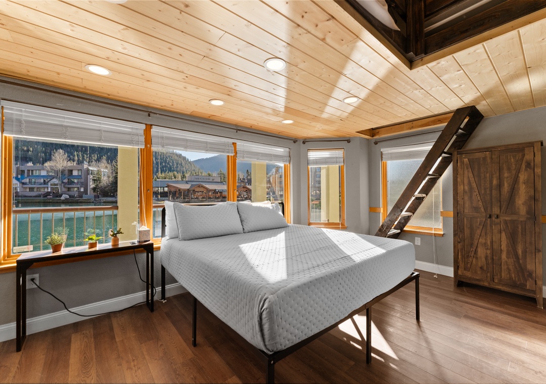 Your serene bedroom features exposed beams, warm wood ceilings, and panoramic lakeside windows that flood the space with natural light.