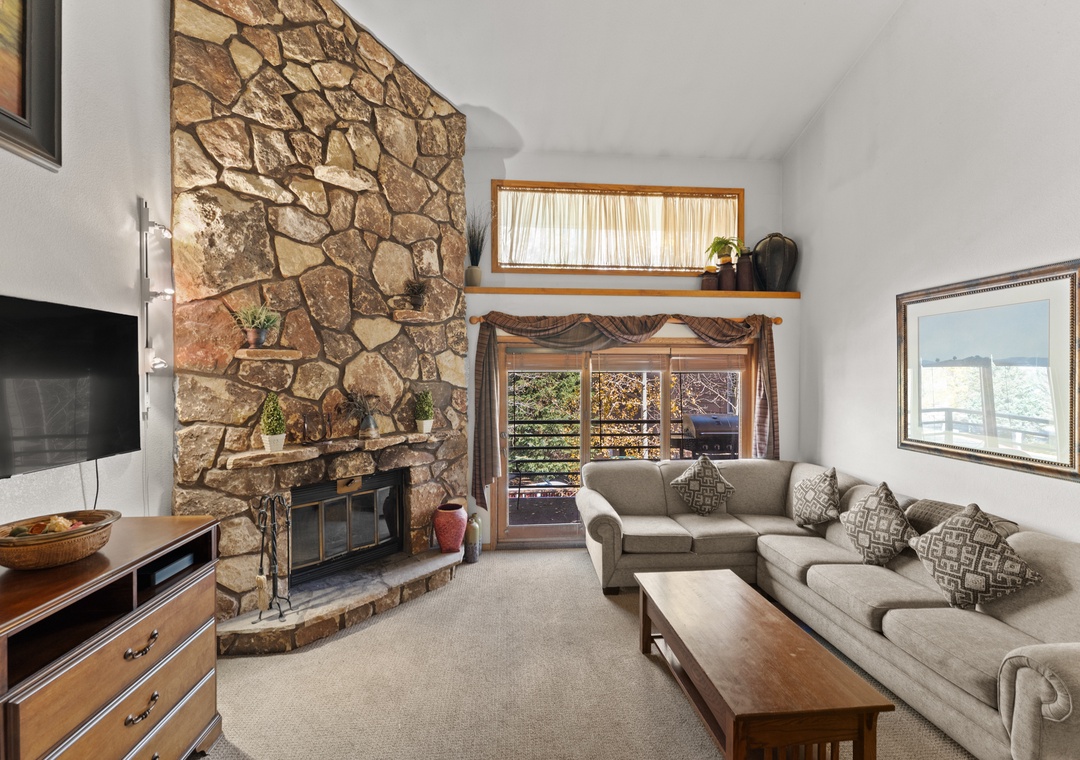 Sink into plush seating beside the stunning stone fireplace, where rustic charm meets modern comfort in your mountain retreat.