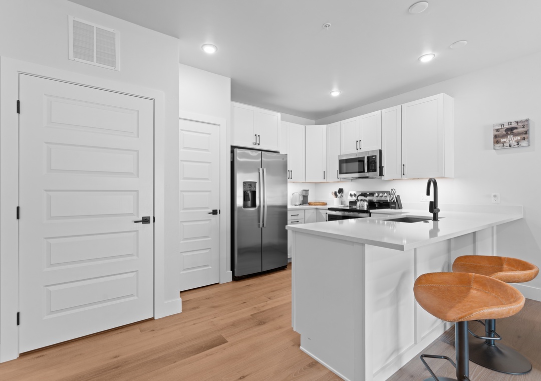 Cook up your favorite meals in this bright, modern kitchen with sleek stainless appliances, ample counter space, and stylish seating at the island—perfect for quick bites or morning coffee.
