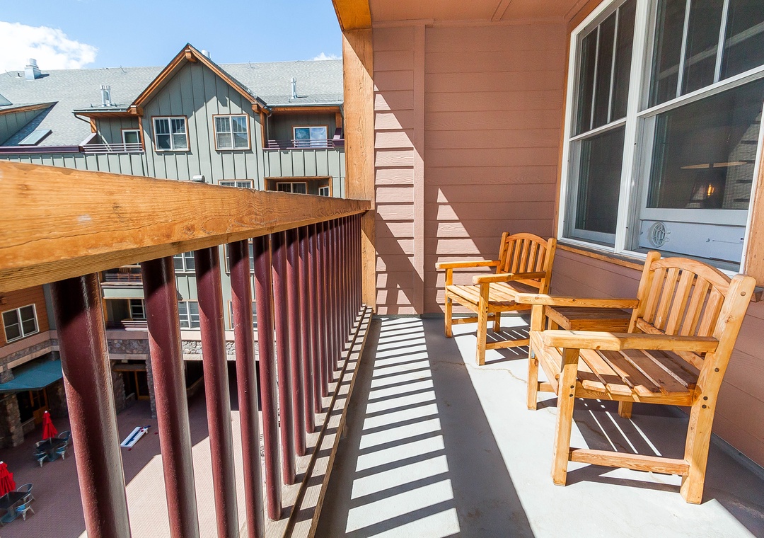 Relax on your private balcony with cozy wooden seating, taking in the charming neighborhood views and fresh mountain air.