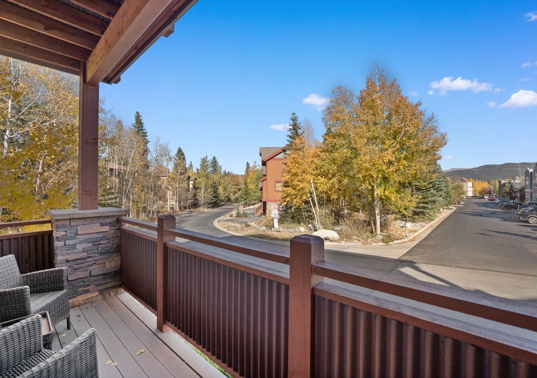 A quiet residential street framed by golden aspens and evergreens, with nearby parking and peaceful mountain surroundings defining the property's welcoming location.