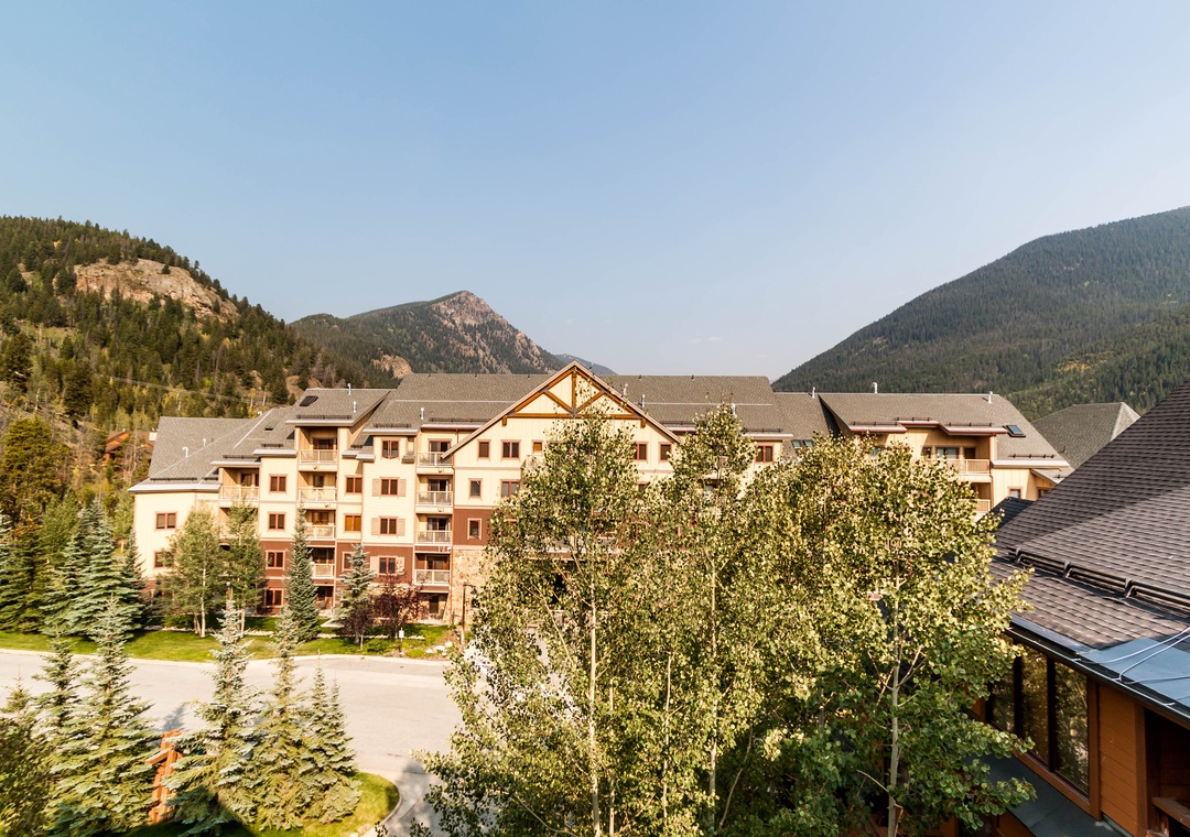 Mountain resort property nestled in a dramatic valley setting with forested peaks and natural alpine landscape.