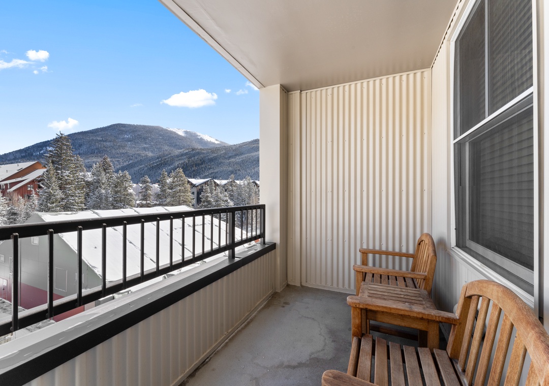 A covered balcony with wooden seating overlooks snow-dusted evergreens and a mountain backdrop—an ideal spot to enjoy crisp winter mornings and scenic alpine vistas.