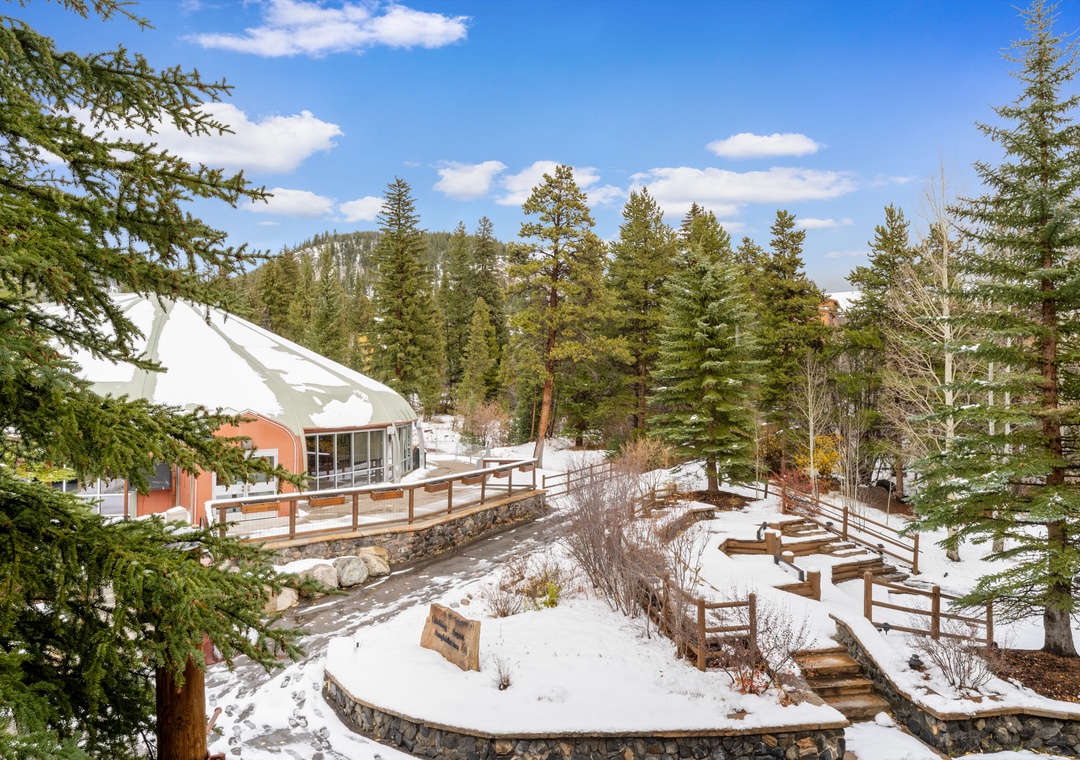 A winter wonderland setting with snow-covered facilities surrounded by evergreen trees and mountain views.