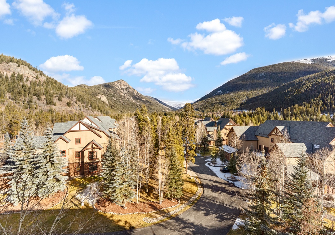 Mountain resort community nestled in a pristine alpine valley with snow-capped peaks and forested slopes creating a stunning natural backdrop.