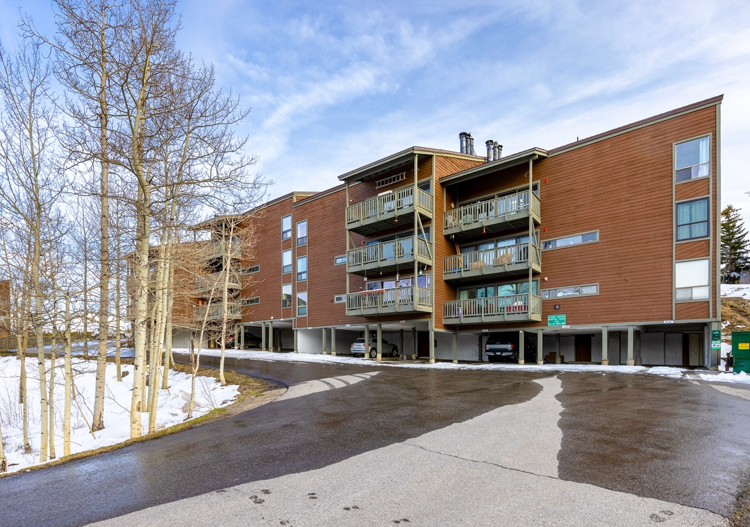 Modern multi-story property featuring wood siding and private balconies, set among snow-dusted aspens with convenient parking access.