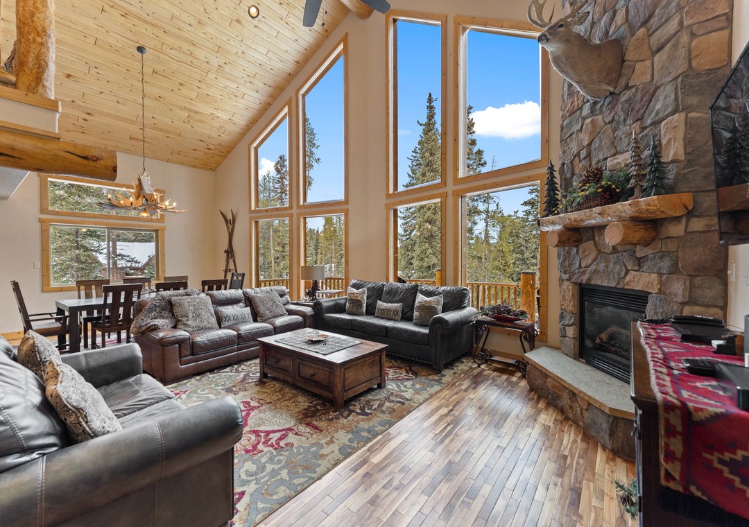 Relax in your spacious mountain retreat with soaring windows framing forest views and cozy stone fireplace perfect for evenings.