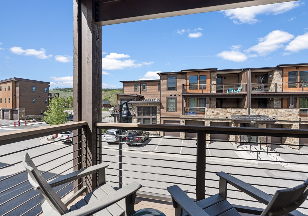 Modern mountain retreat with private balcony overlooking vibrant neighborhood, where blue skies and rolling hills frame your cozy outdoor escape.