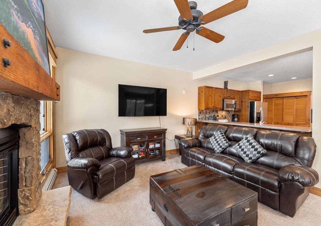Unwind in your cozy living space with leather seating, stone fireplace, and open kitchen perfect for family gatherings.